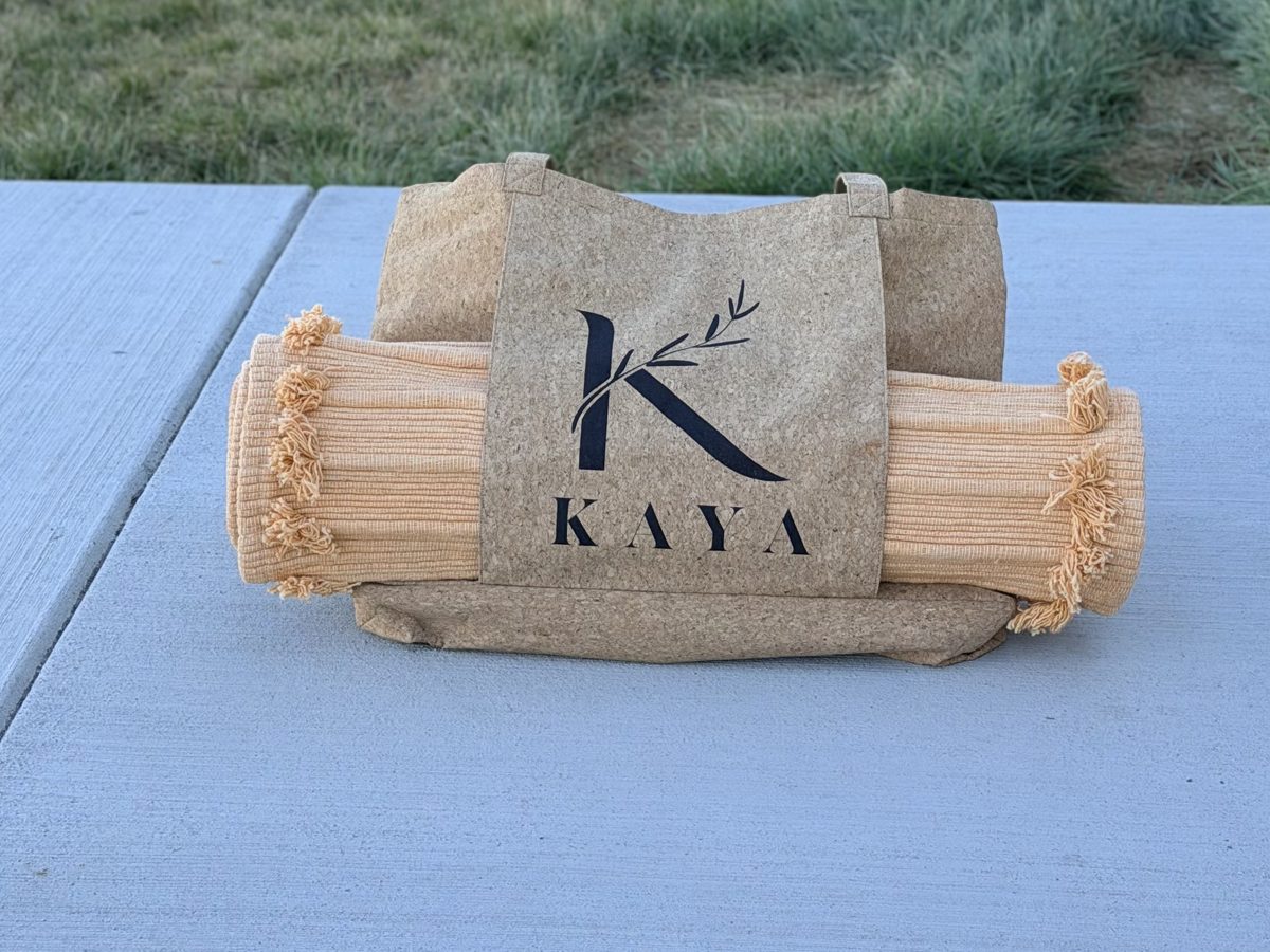 Handloomed cotton yoga rug rolled inside a Kaya cork tote on a patio